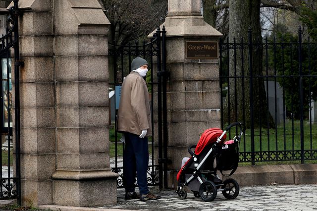 A man wearing a mask with a baby stroller tries to enter Green-Wood Cemetery on April 8, 2020